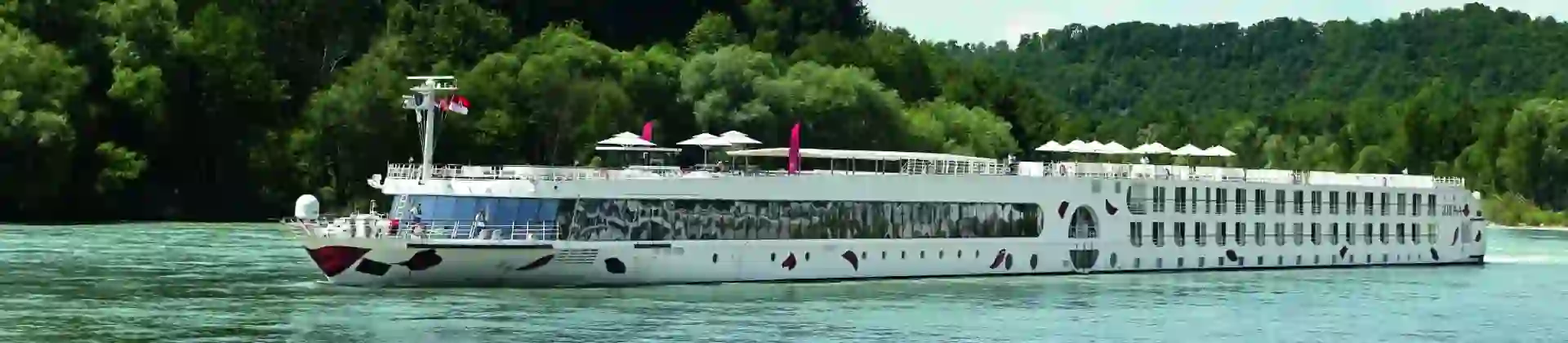 An A-ROSA river cruise ship sailing down a river with trees in the background