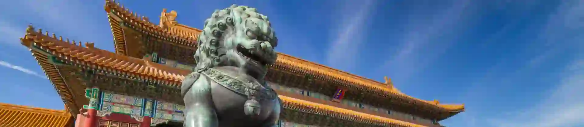Bronze guardian lion outside ornate palace buildings in the Forbidden City, Beijing, China