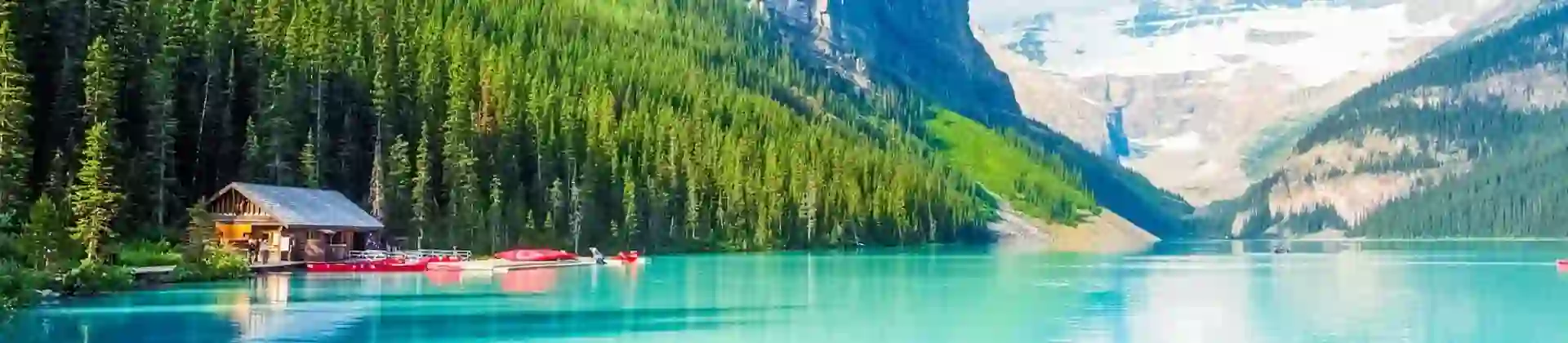 Turquoise waters of Lake Louise surrounded by forested slopes and snow-capped mountains