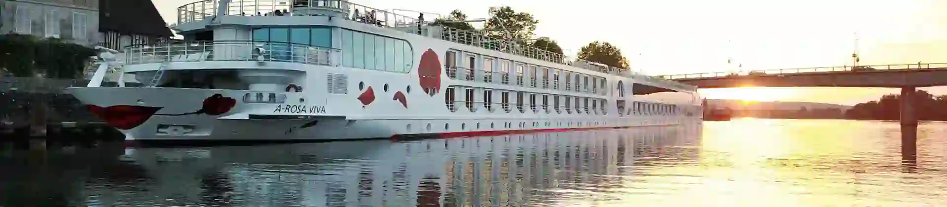 A-ROSA VIVA cruise ship on a calm city river at sunset, with a bridge in the background