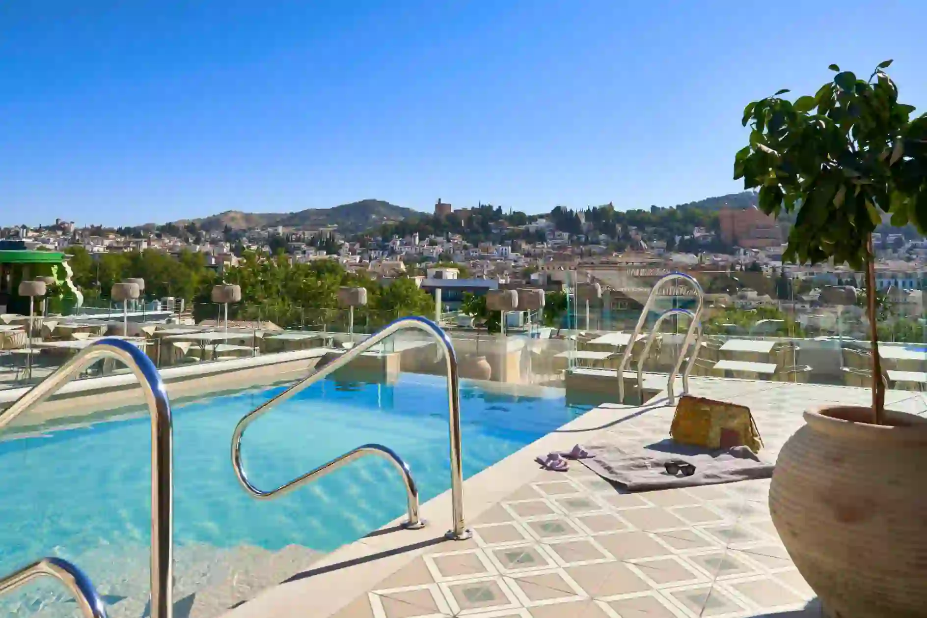 The rooftop pool at Barceló Carmen Granada hotel with views of the city and mountains in the distance on a sunny day