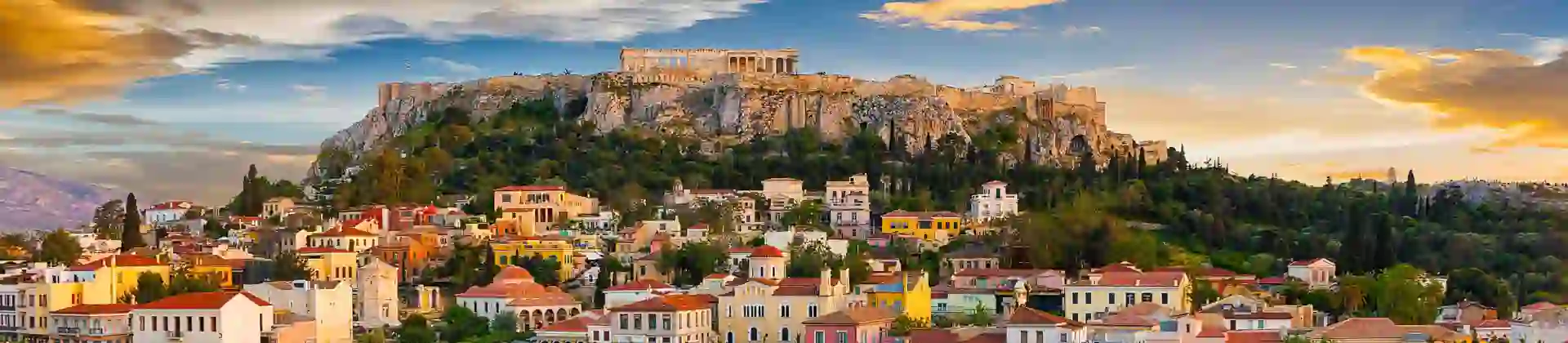 View of a city with colourful buildings and a rocky hill with ruins on the top.