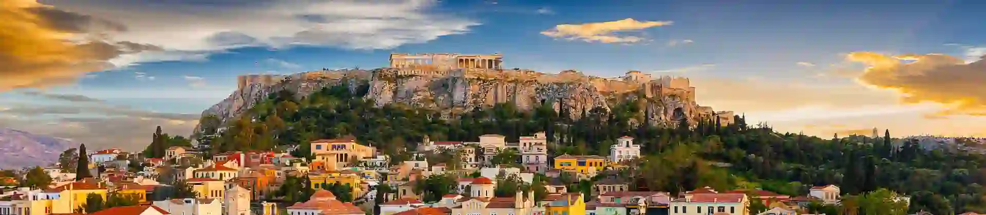 View of a city with colourful buildings and a rocky hill with ruins on the top.