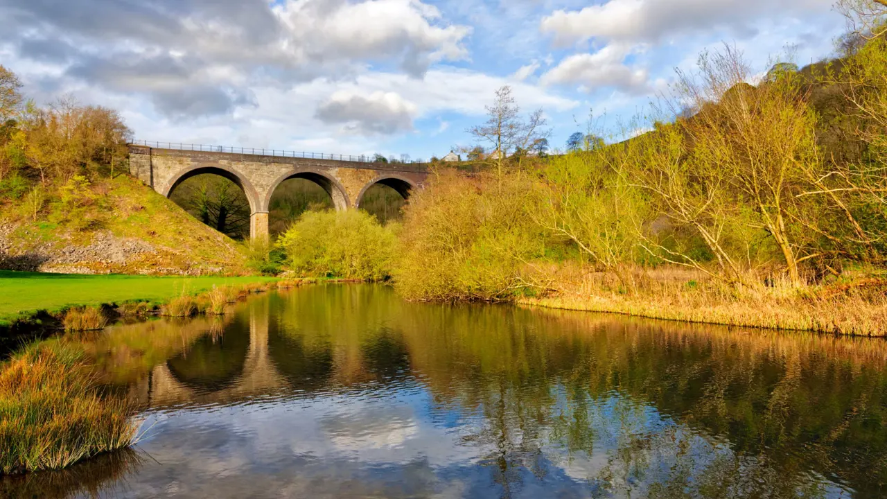 Shot of Headstone Viaduct and the river, with trees either side