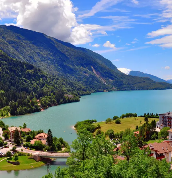 Shot of Molveno Lake in Italy, with buildings in the forefront and mountains 