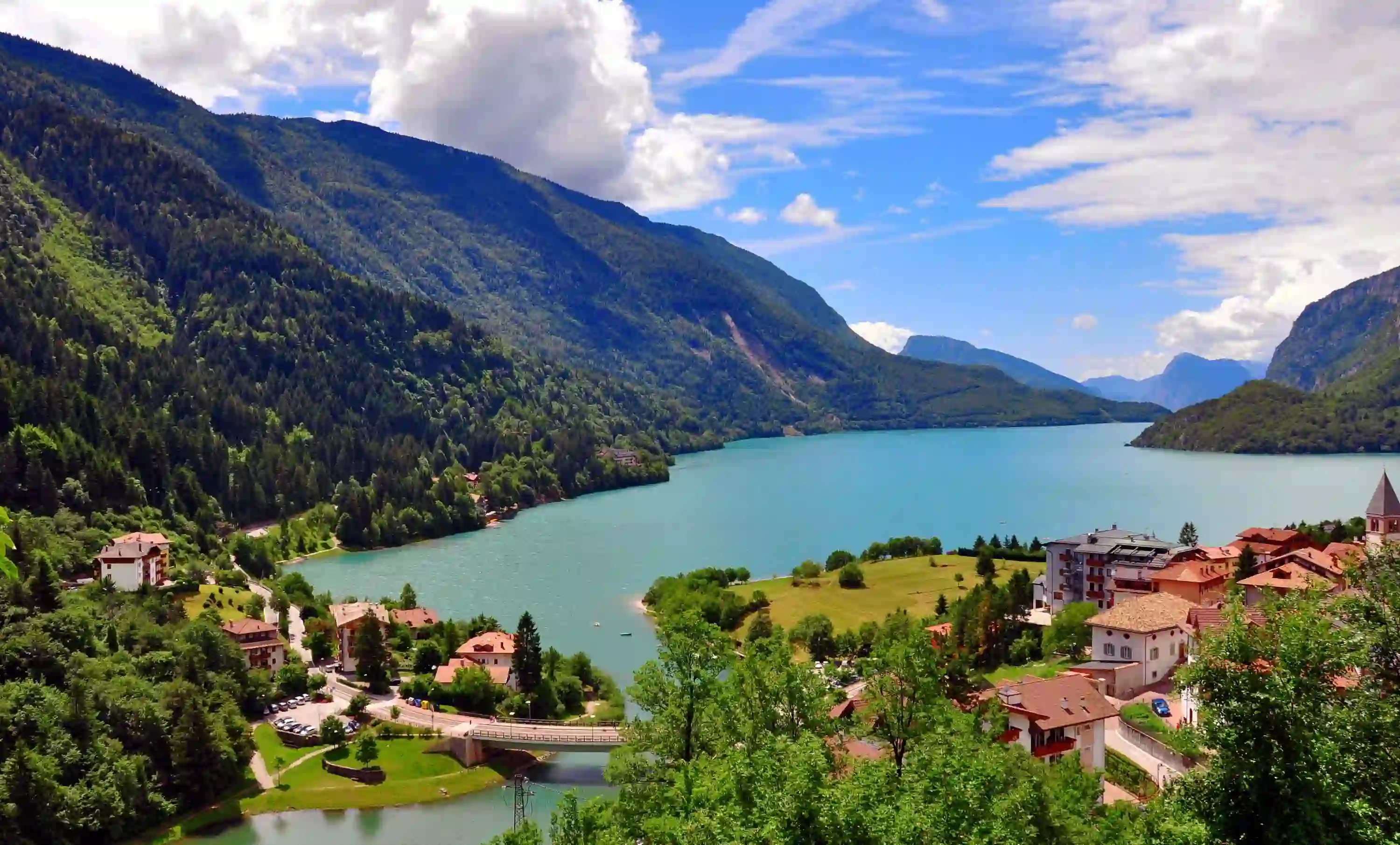 Shot of Molveno Lake in Italy, with buildings in the forefront and mountains 