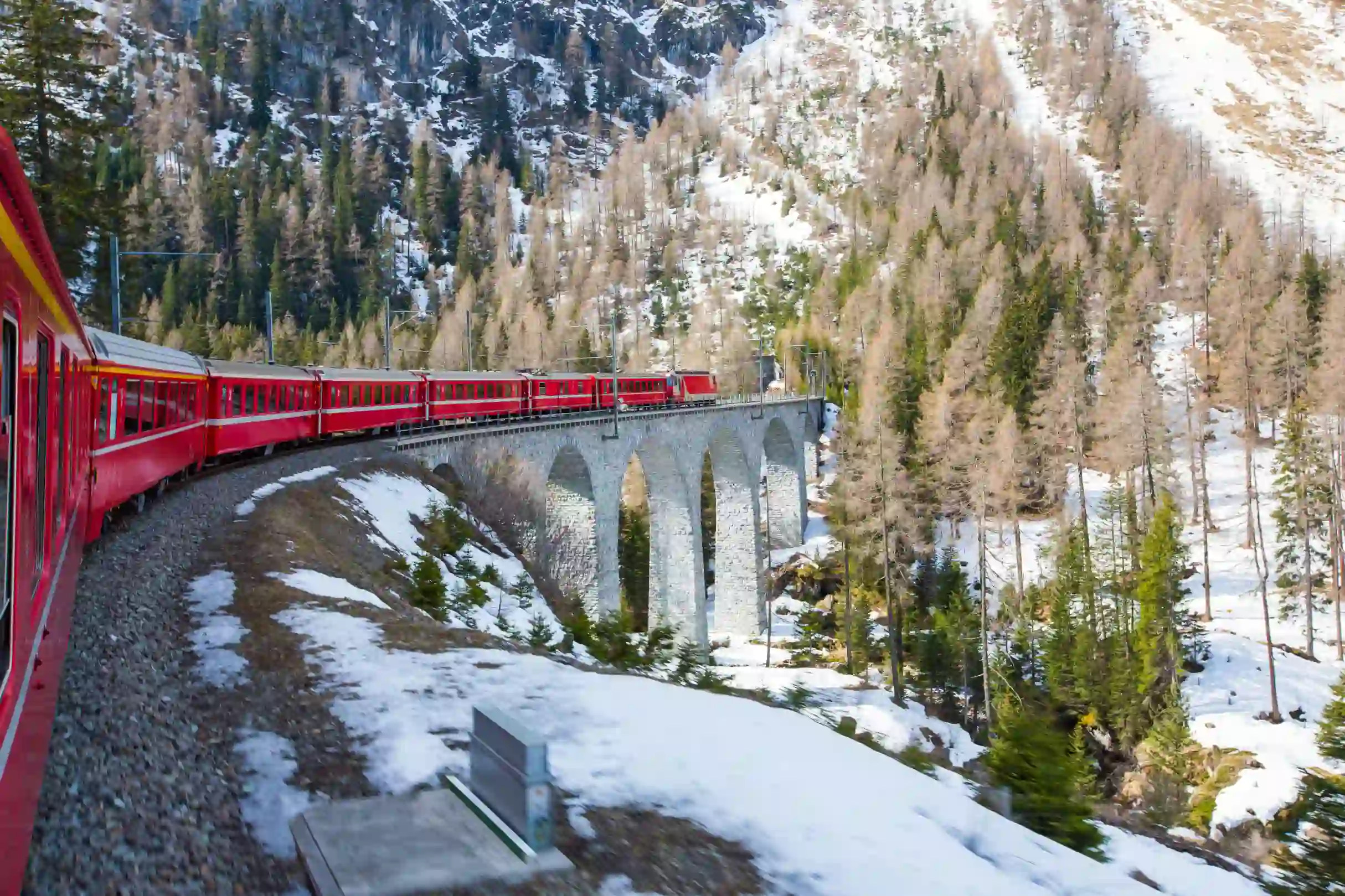 The Bernina Express going along the railway in the mountains, in the snow