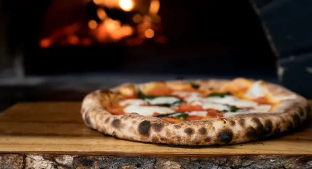 Pizza with woodfire oven in the background in Naples, Italy