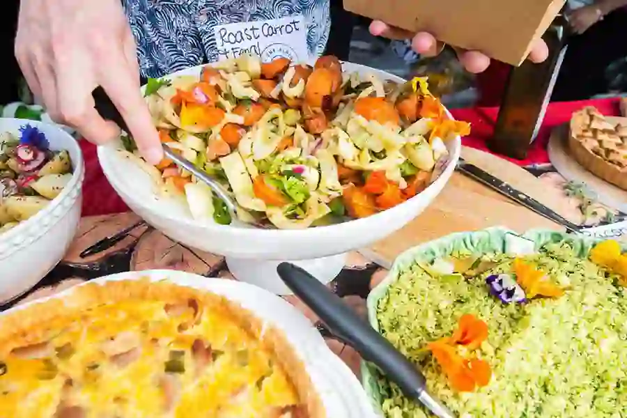 Close up of a variety of dishes, a hand serving a salad