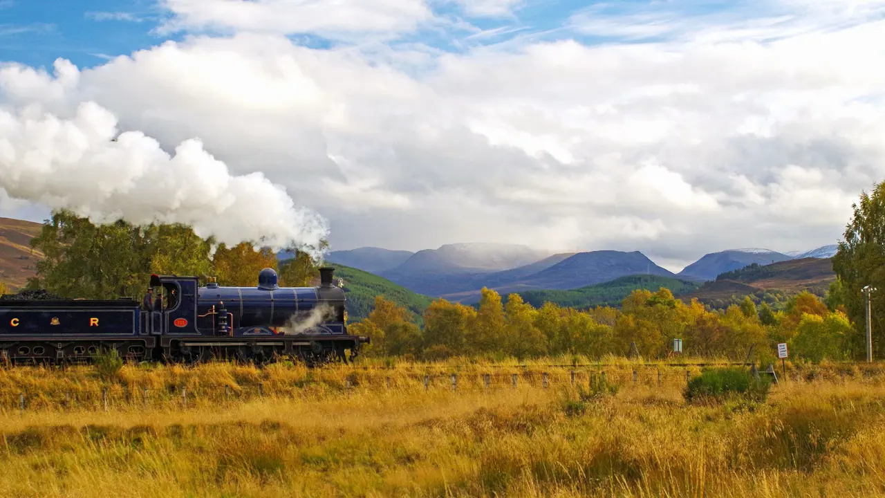 Steam train approaches Kinchurdy Bridge against Cairngorms 