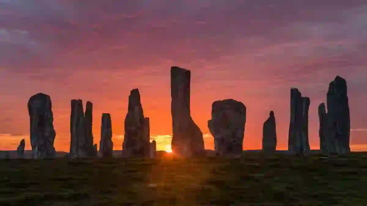 Silhouette of Calanais Standing Stones, with the sun rising behind them 