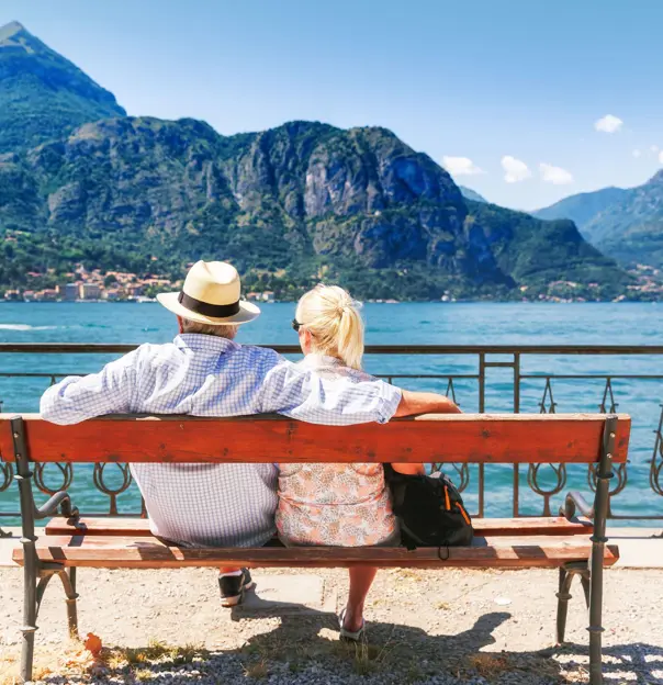 The back of a couple sat on a bench looking out to Lake Como