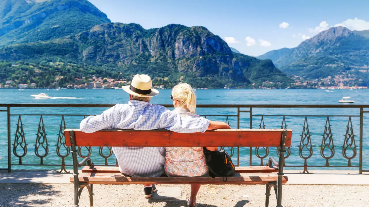 The back of a couple sat on a bench looking out to Lake Como