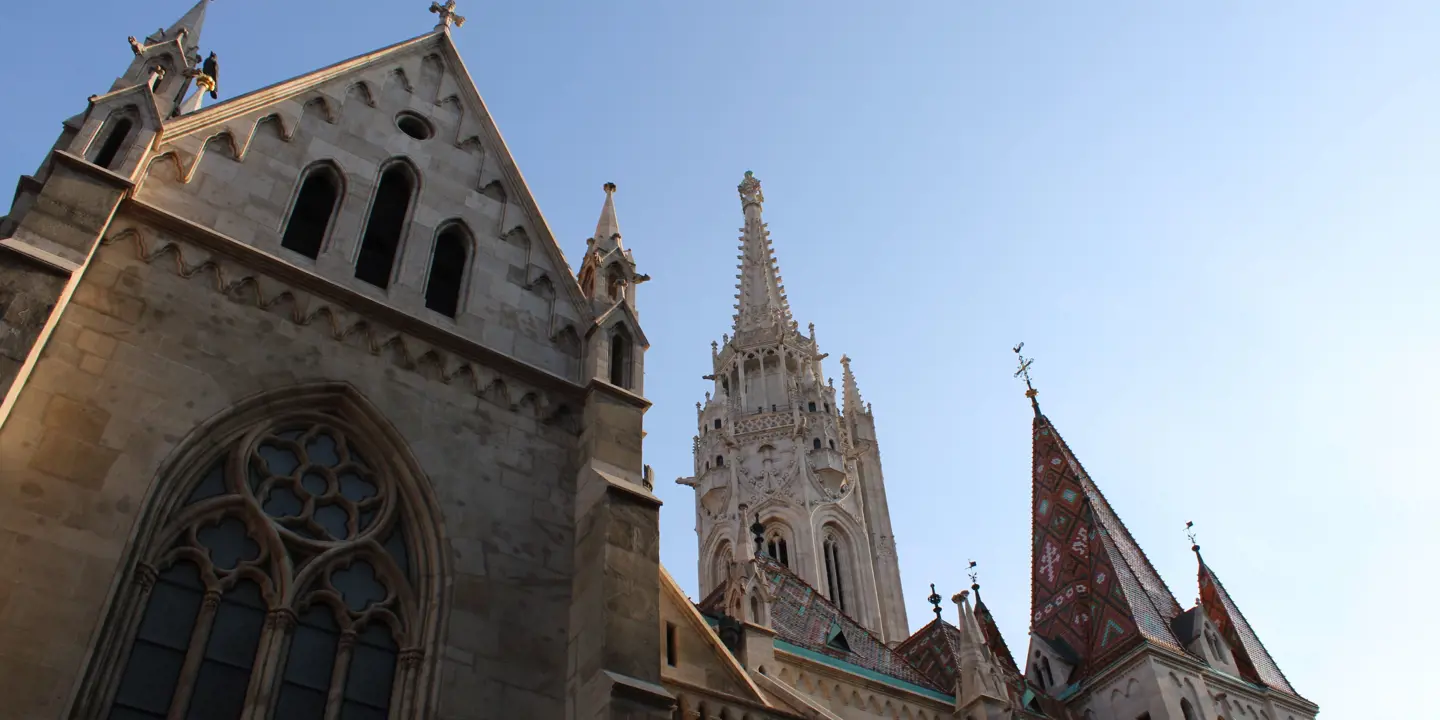 Low angle shot of Mátyás Church, with spiked turrets and triangular roofs.