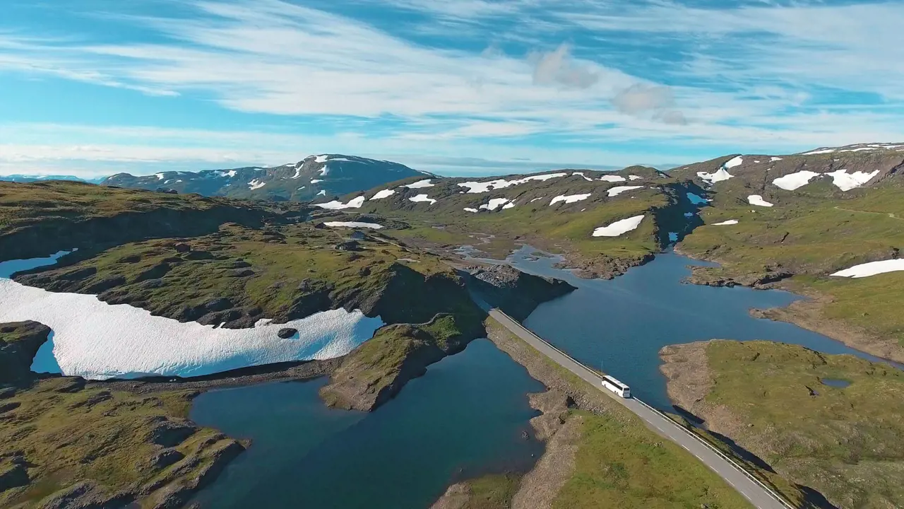 Fjord of Norway with surrounding land and road with a coach driving on it