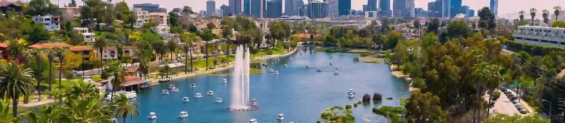 View of Los Angeles with a lake in the foreground, boats on the water, and the city skyline in the background