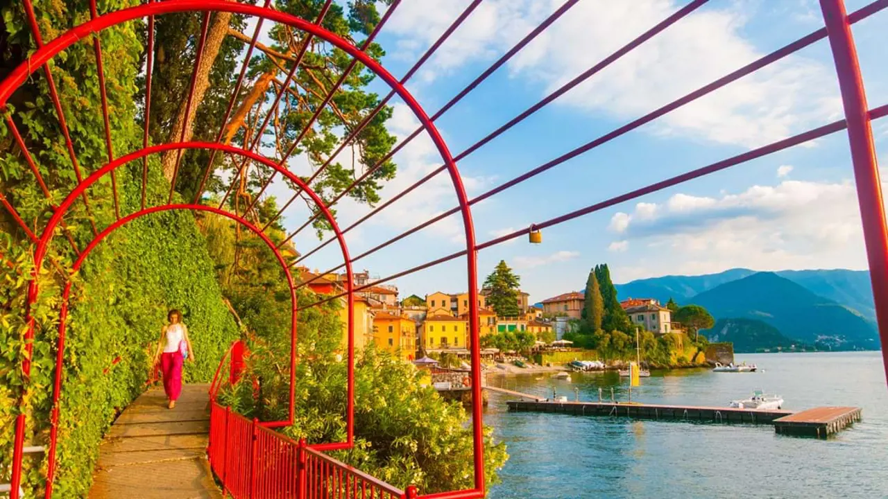 Red gate archway in Varenna, Lake Como, showing a woman approaching on the walkway