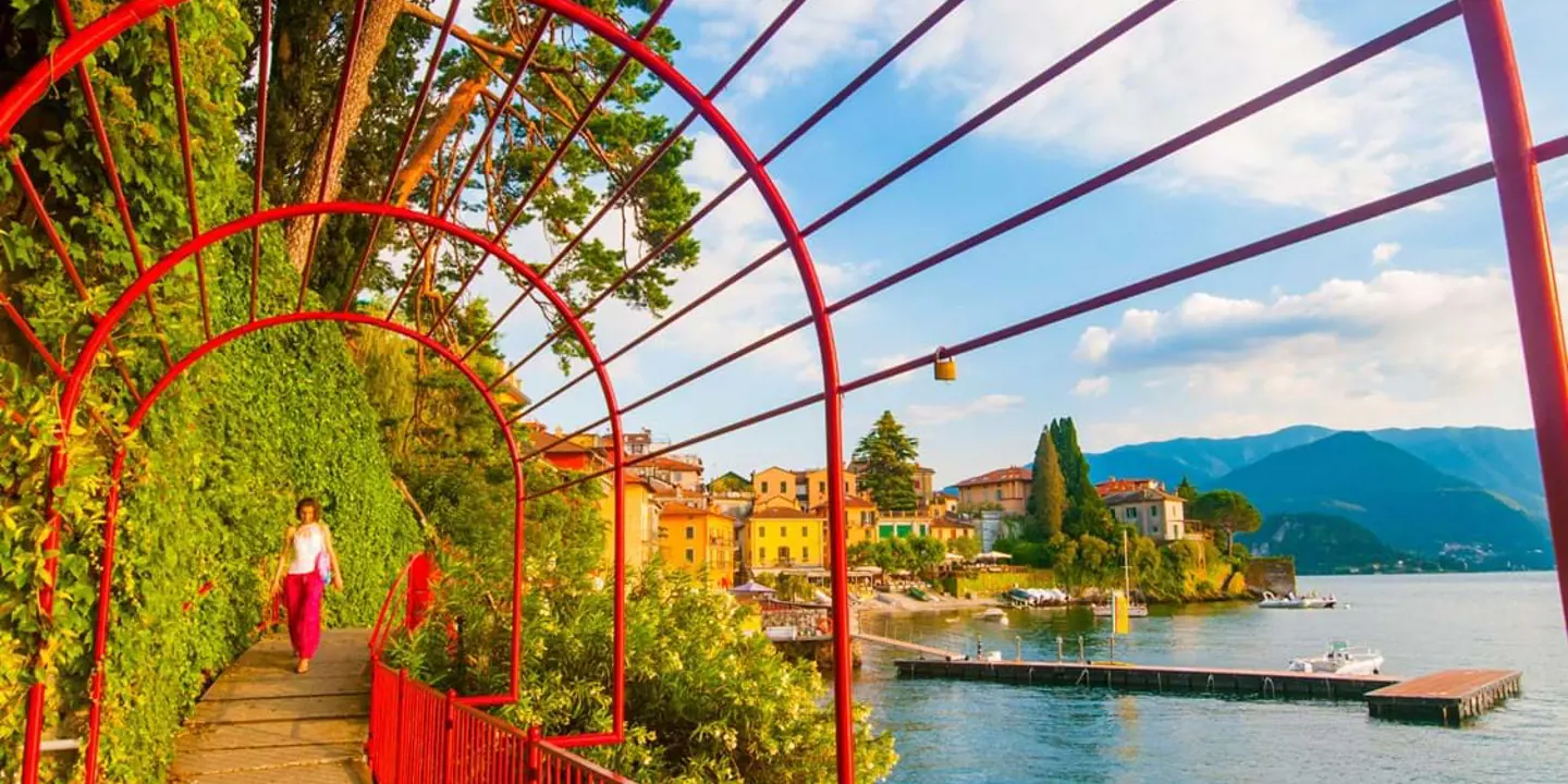 Red gate archway in Varenna, Lake Como, showing a woman approaching on the walkway