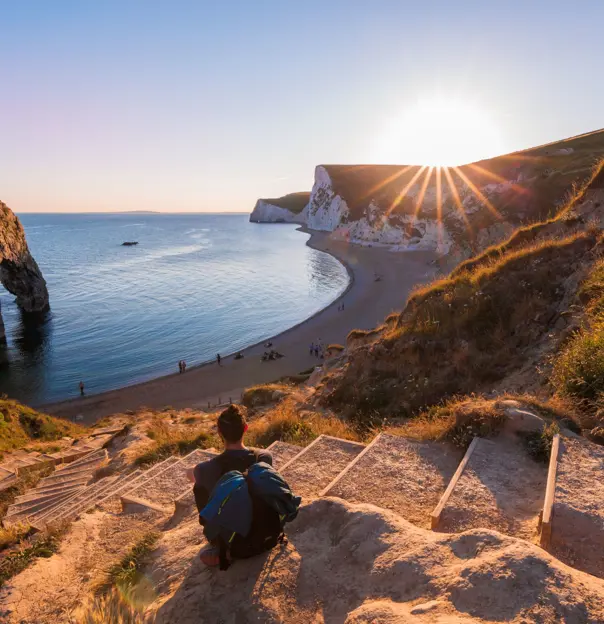 Person sitting on steps overlooking the beach on the Jurassic Coast Dorset 