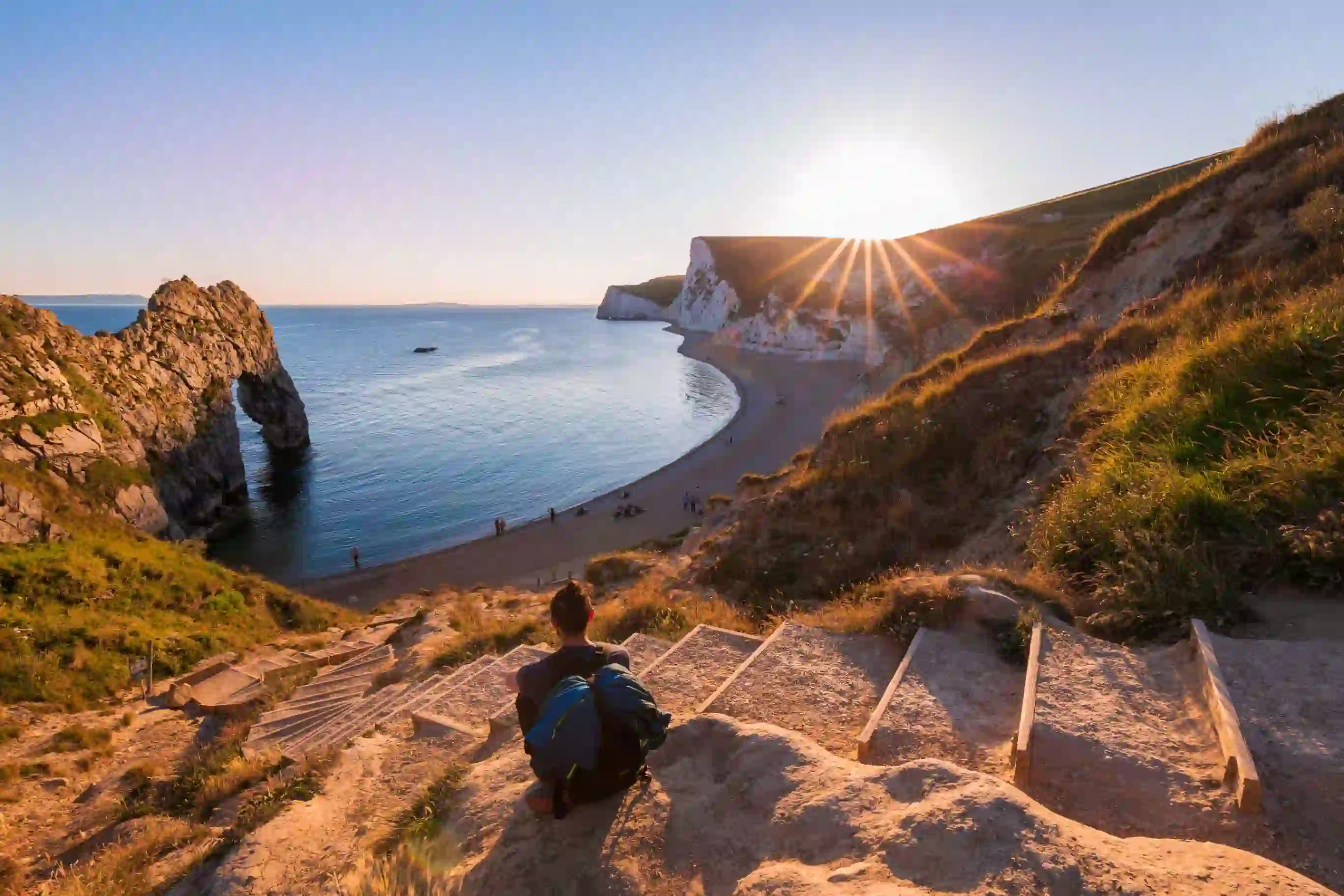 Person sitting on steps overlooking the beach on the Jurassic Coast Dorset 