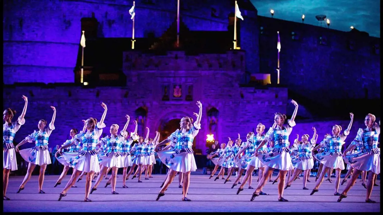 Highland female dancers dancing in unison outside Edinburgh Castle under purple lighting