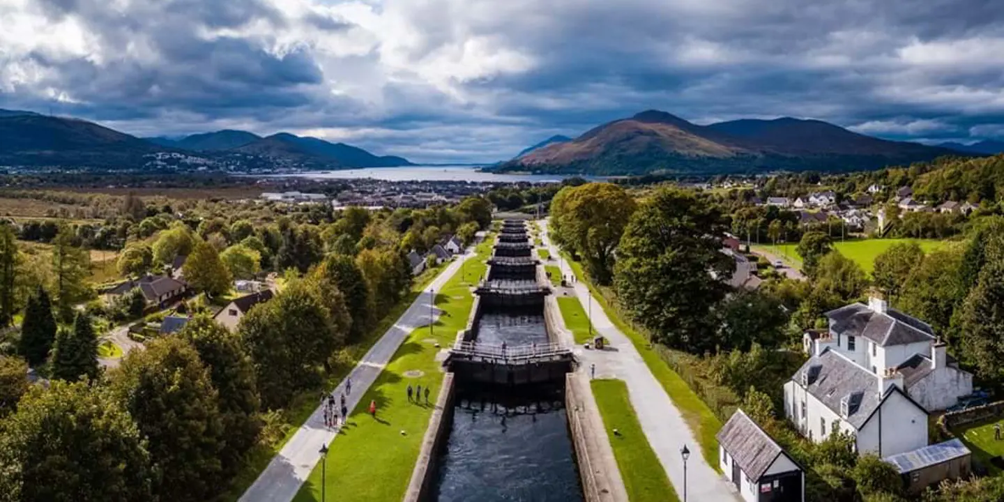 High angle shot of the Caledonian Canal, showing the houses and tress either side and loch and mountains in the distance