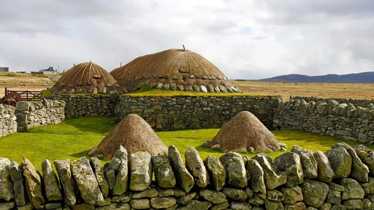  Arnol Black House, with mounds of hay surrounded by a stone wall in the forefront