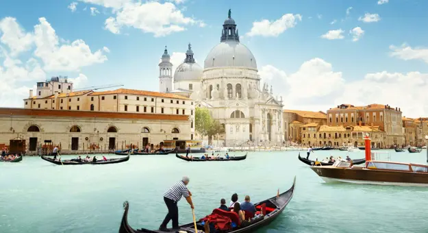 View of gondola boats travelling on the water and the Salute Church in Venice, Italy