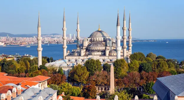 Exterior view of the Blue Mosque in Istanbul, Turkey, showing its domes and six minarets against a clear sky