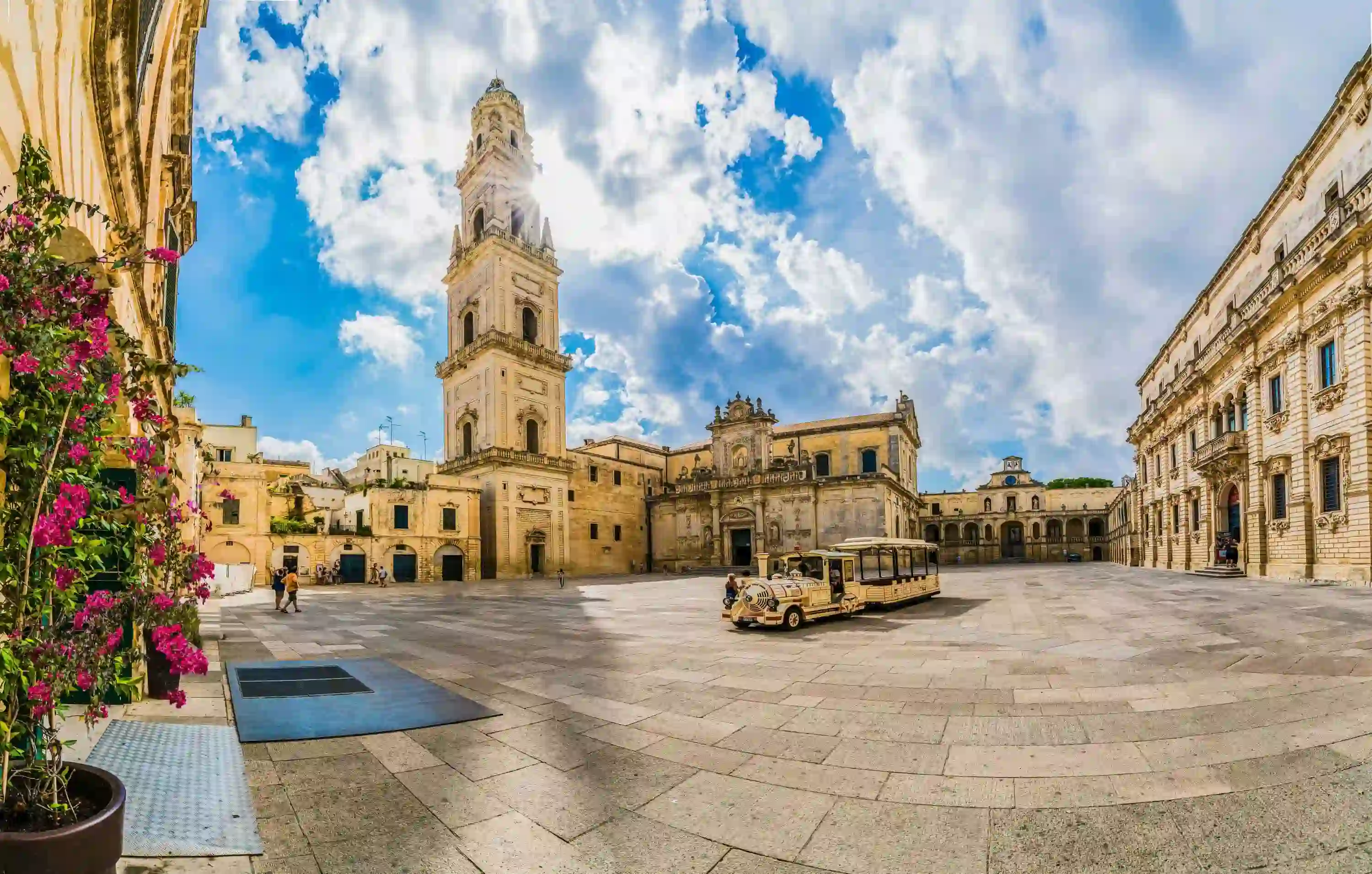 Square in Lecce, Italy, showing a tower and touring vehicle 