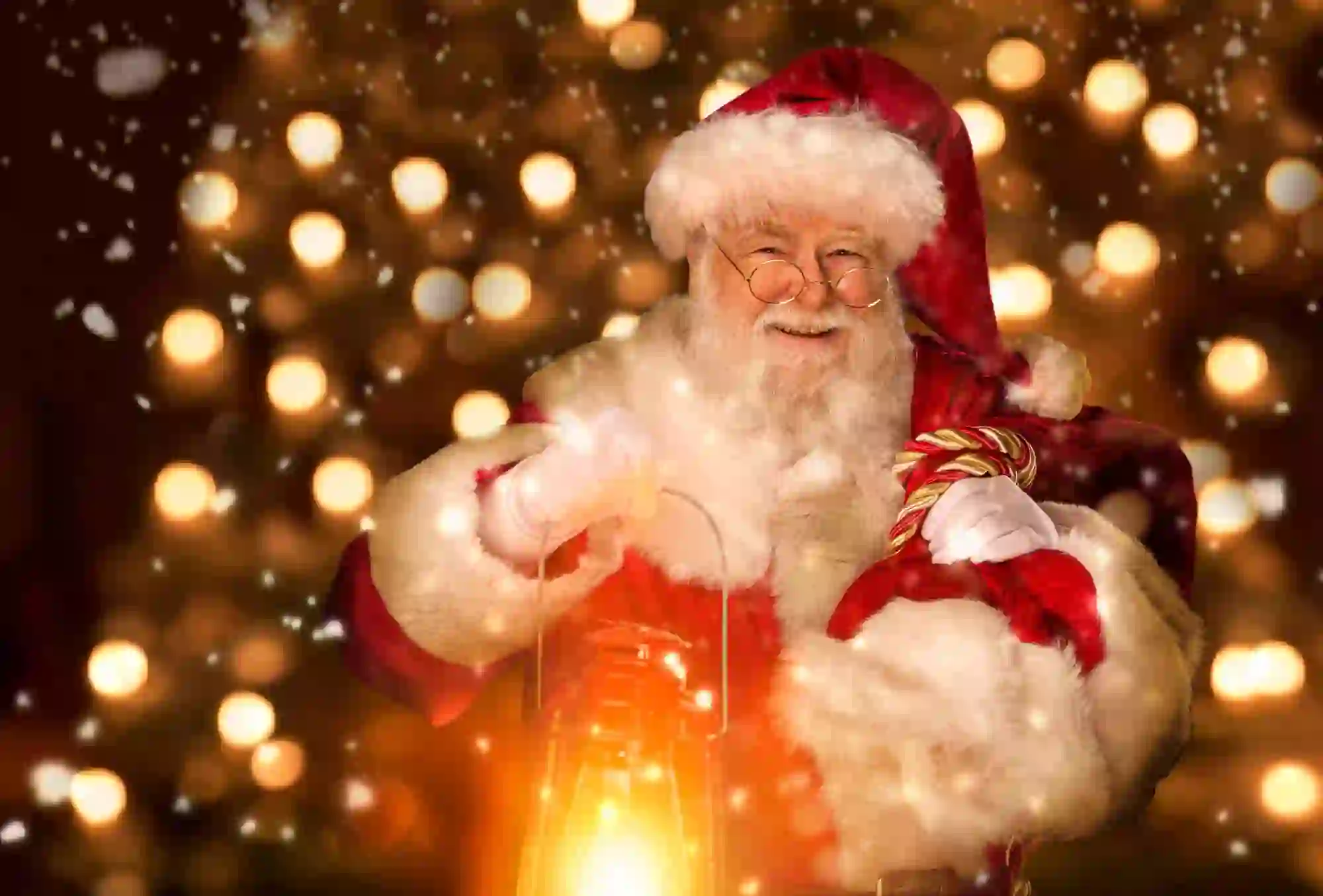 Santa holding a lantern and smiling, with a background of fairy lights