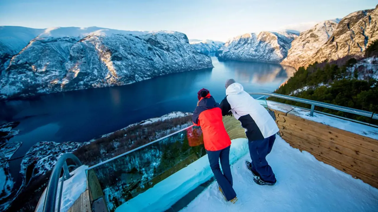 Two people looking out over a fjord in the snow