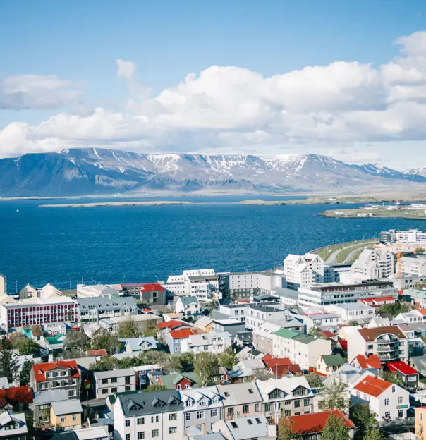 Predominately white houses and buildings of Reykjavik on the waterfront. View of mountains in the distance