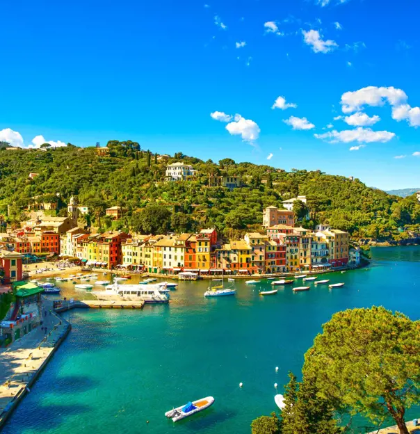 View of a small beach in Portofino, showing boats on the water and buildings on the waterfront