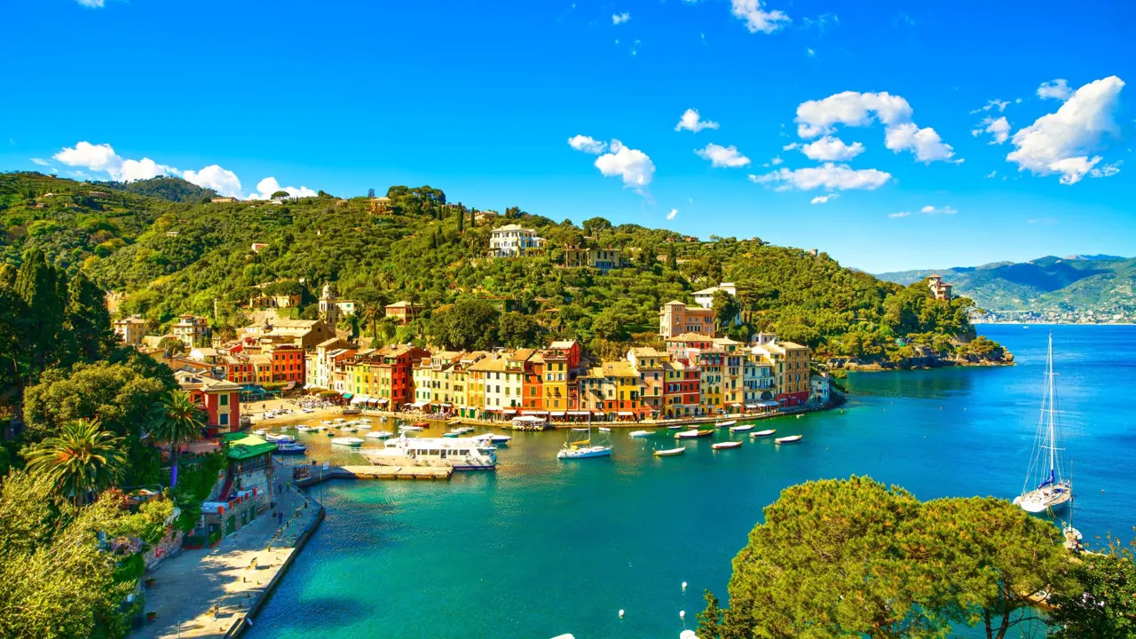 View of a small beach in Portofino, showing boats on the water and buildings on the waterfront