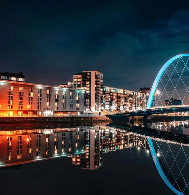 View of the city of Glasgow at night time, with the buildings lit up and The Clyde Arc on the right