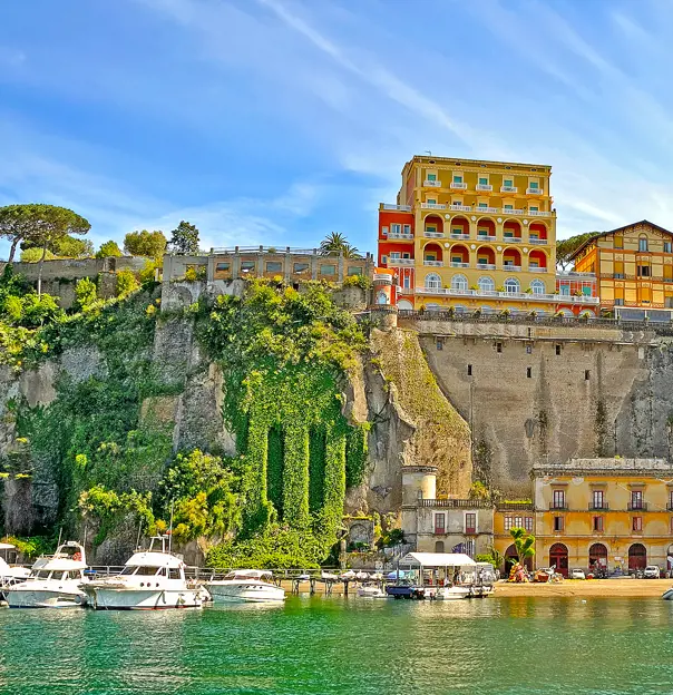 View of Sorrento from the water, with boats in the forefront, stone wall and buildings