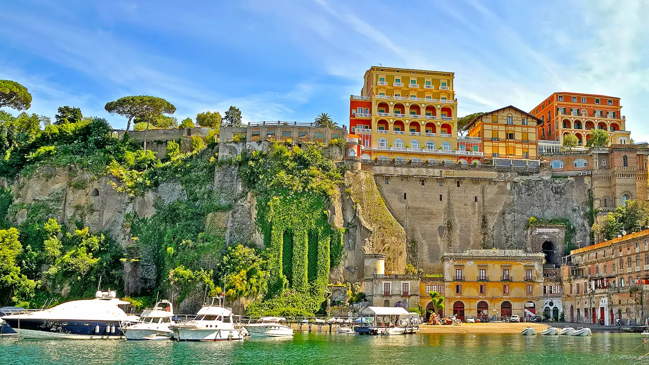 View of Sorrento from the water, with boats in the forefront, stone wall and buildings