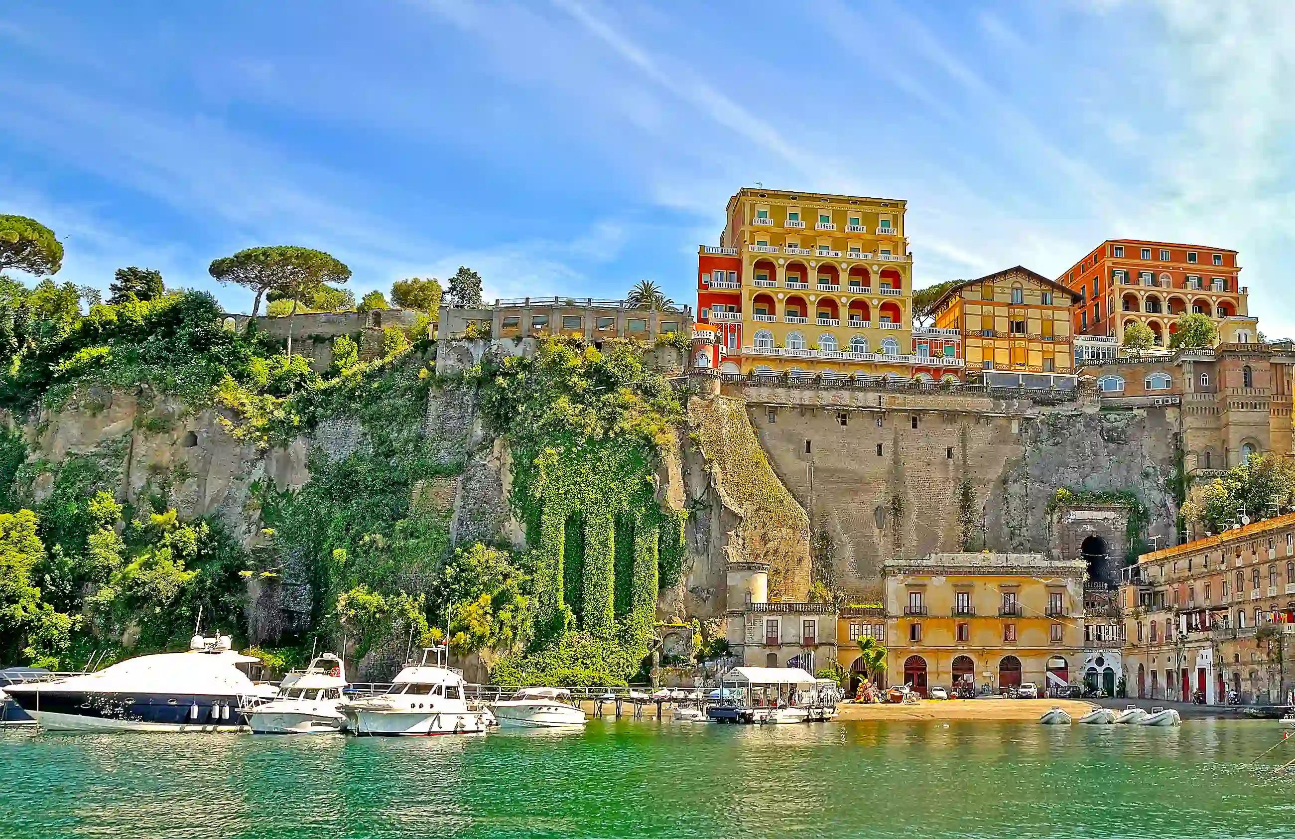 View of Sorrento from the water, with boats in the forefront, stone wall and buildings