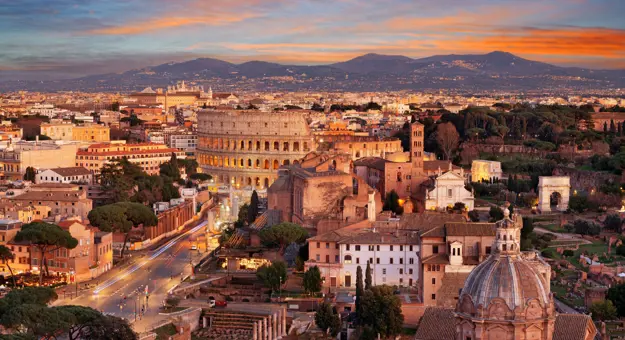 Cityscape of Rome at sunset, showing the Colosseum and St. Peter's Basilica 