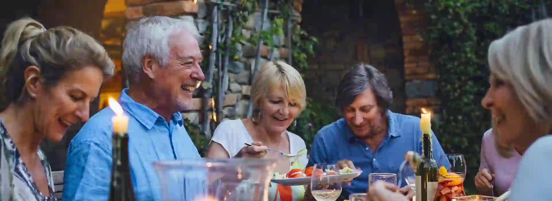 People around a table eating al fresco & sharing food by candlelight 