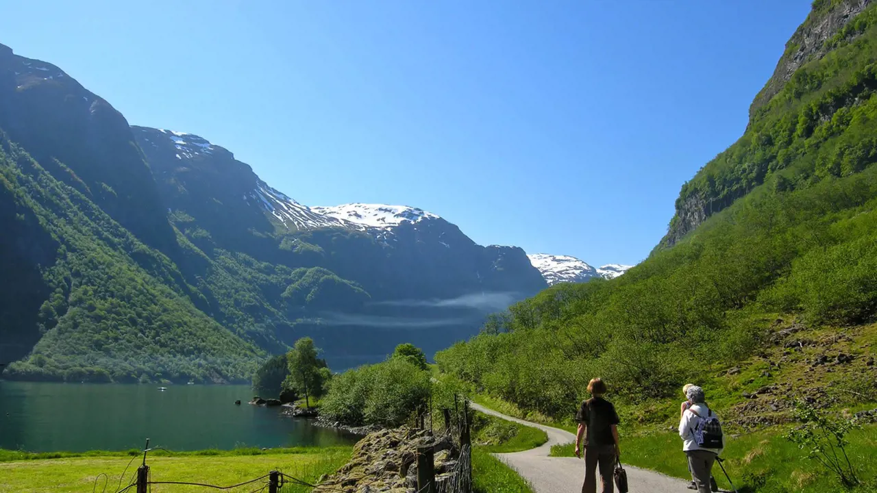 3 people hiking by The Naroyfjorden, with mountain in the distance