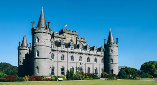 Shot of Inveraray Castle on a sunny day, with a blue sky and green grass infront 