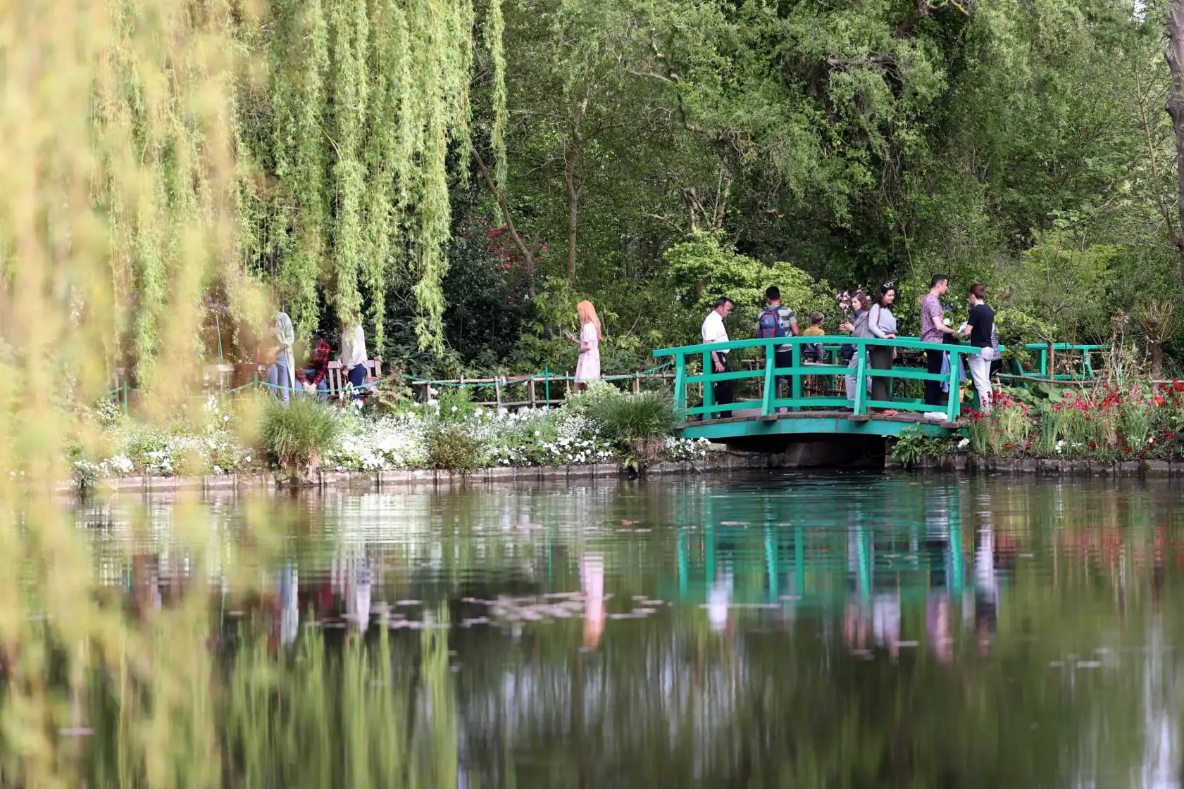 People walking over the iconic wooden bridge above the pond in Claude Monet’s ga