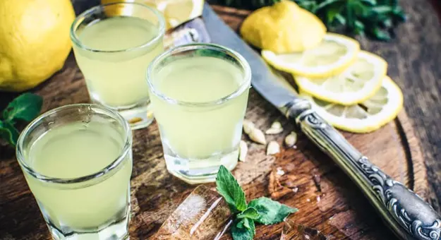 Close up of glasses of Limoncello, with lemons next to them