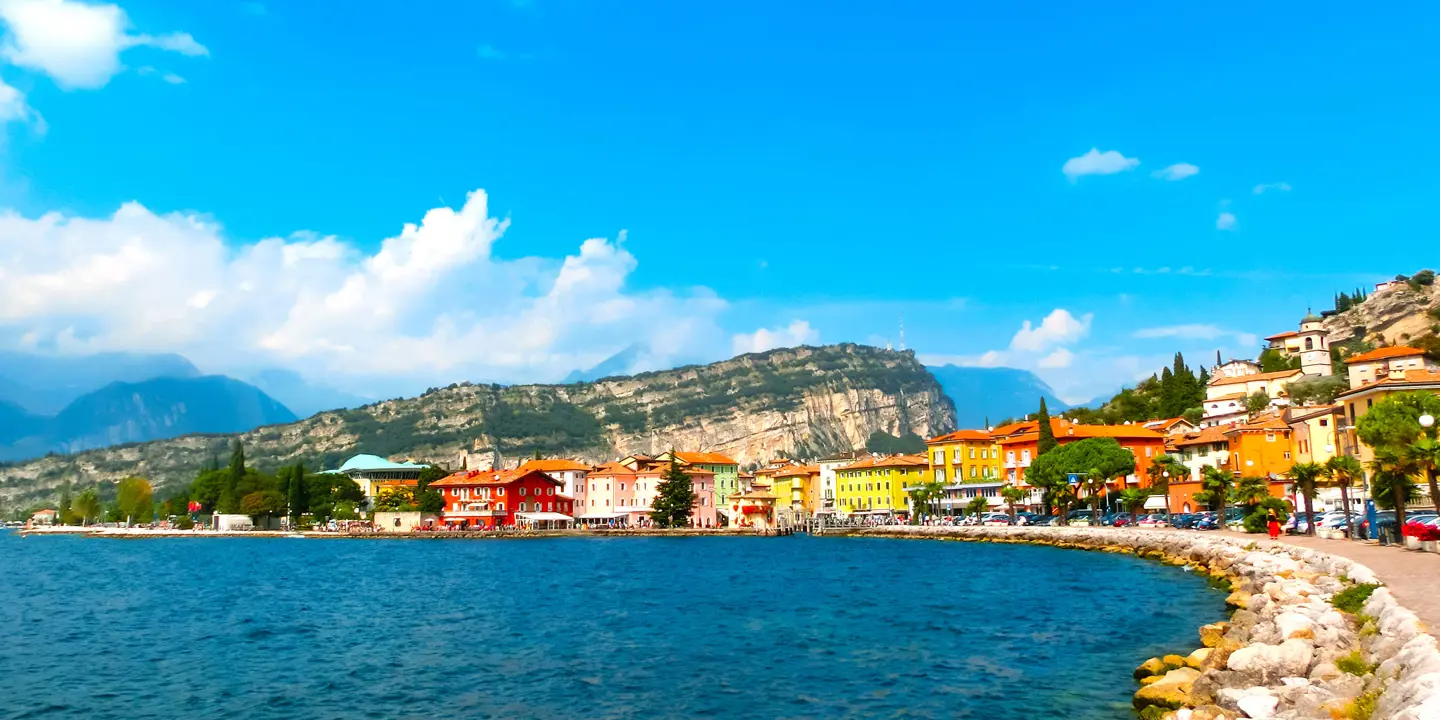 Waterfront in Torbole, Lake Garda, showing pavement and buildings and mountains in the distance