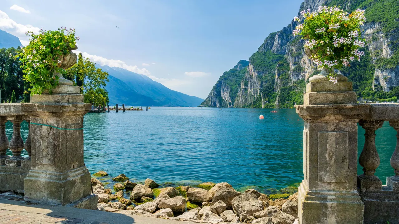 View of Riva Del Garda with bouquets of flowers in the forefront and mountains in the distance