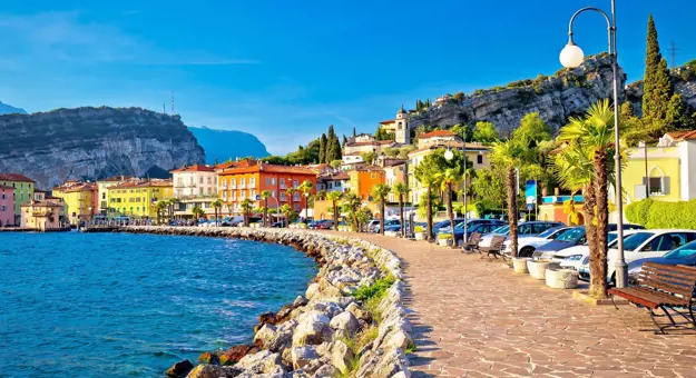 Waterfront in Torbole, Lake Garda, showing pavement and buildings and mountains in the distance